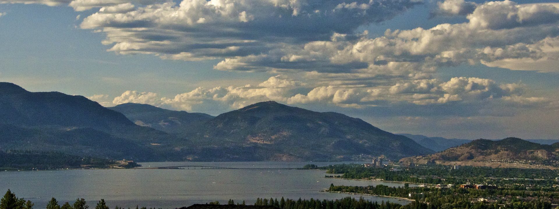 Okanagan Lake at Kelowna under a sky full of cumulus clouds, the bridge across the lake below